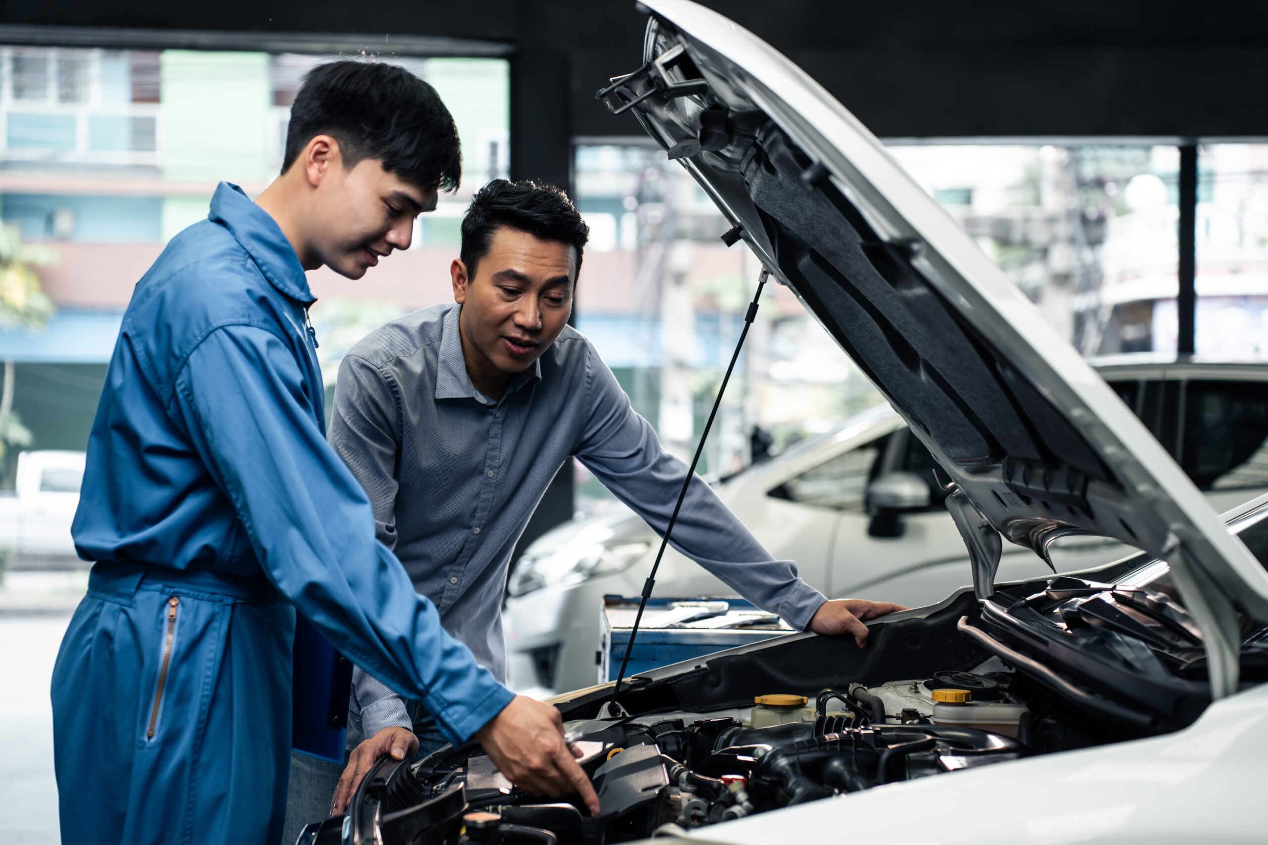 Asian,Automotive,Mechanic,Explain,Car,Condition,To,Client,In,Garage.